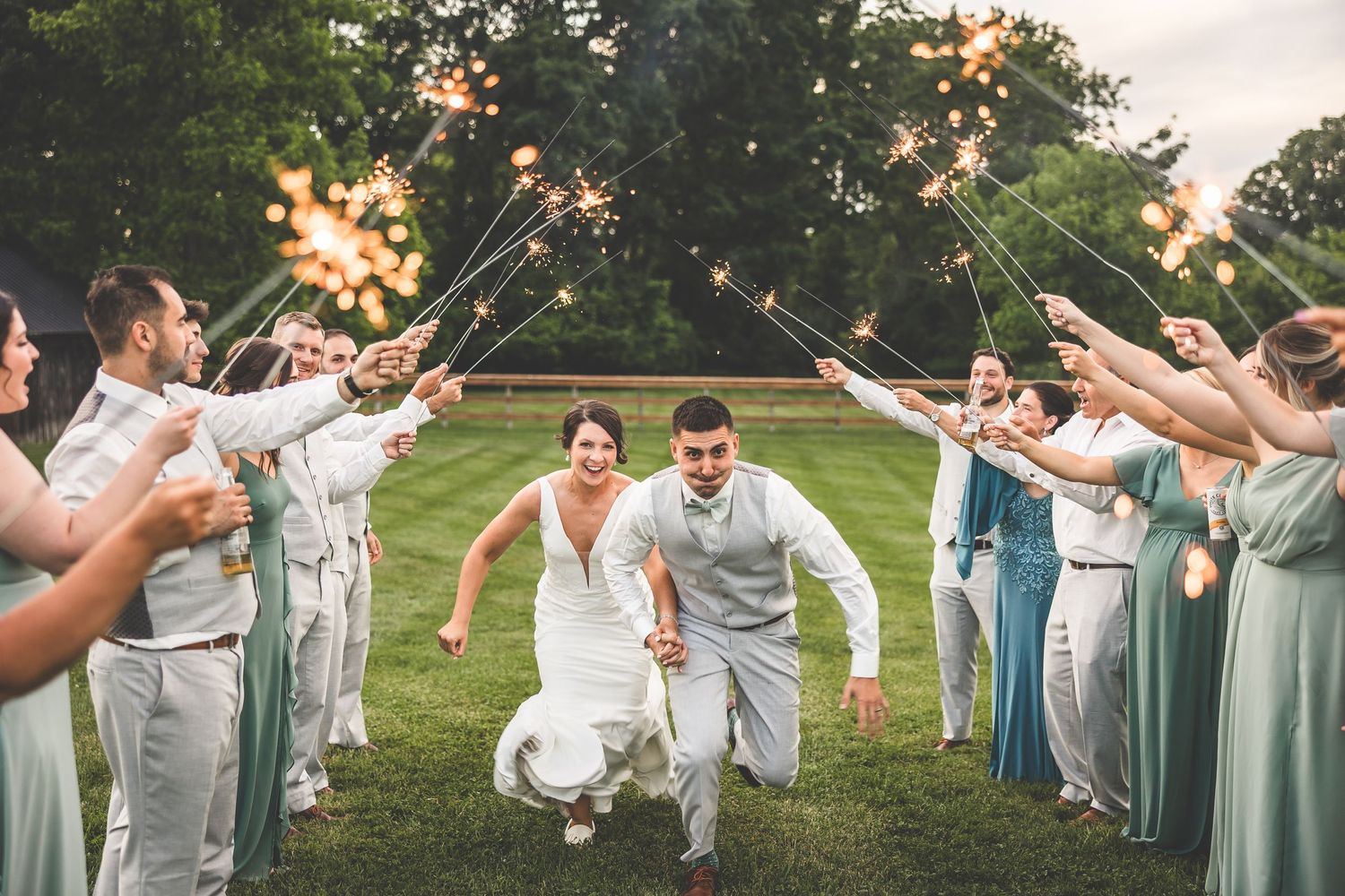 Wedding guests forming a tunnel with sparklers as couple walks through.