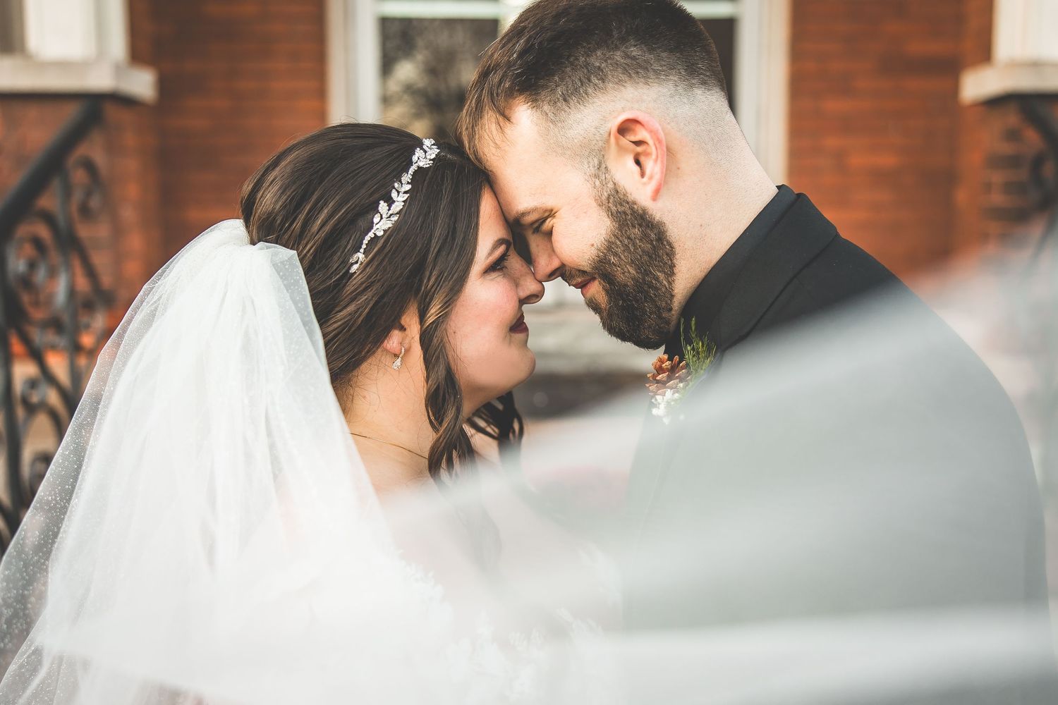 Wedding couple shares intimate moment under flowing veil.