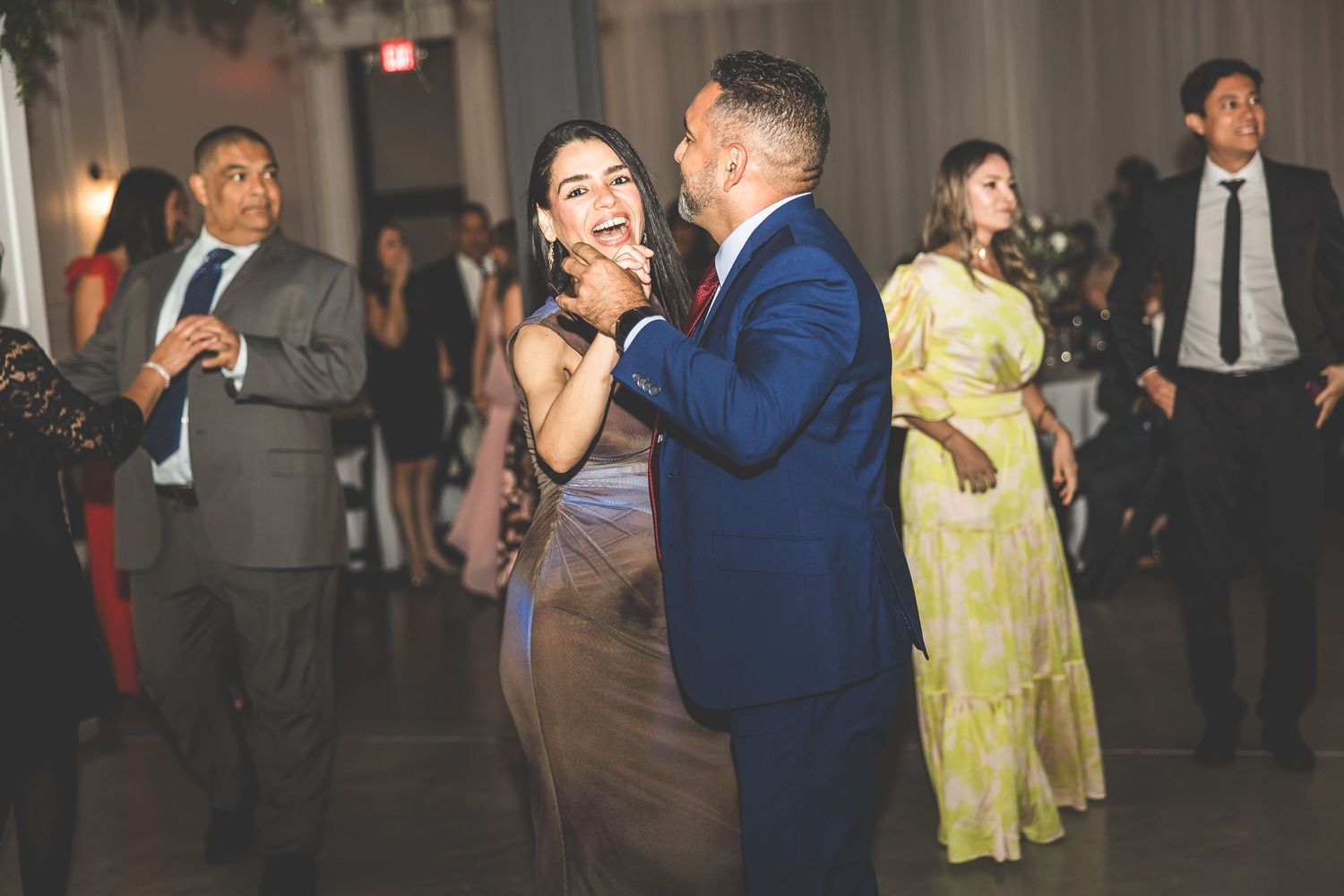 Wedding reception guests enjoying dances together in a beautifully lit ballroom venue.