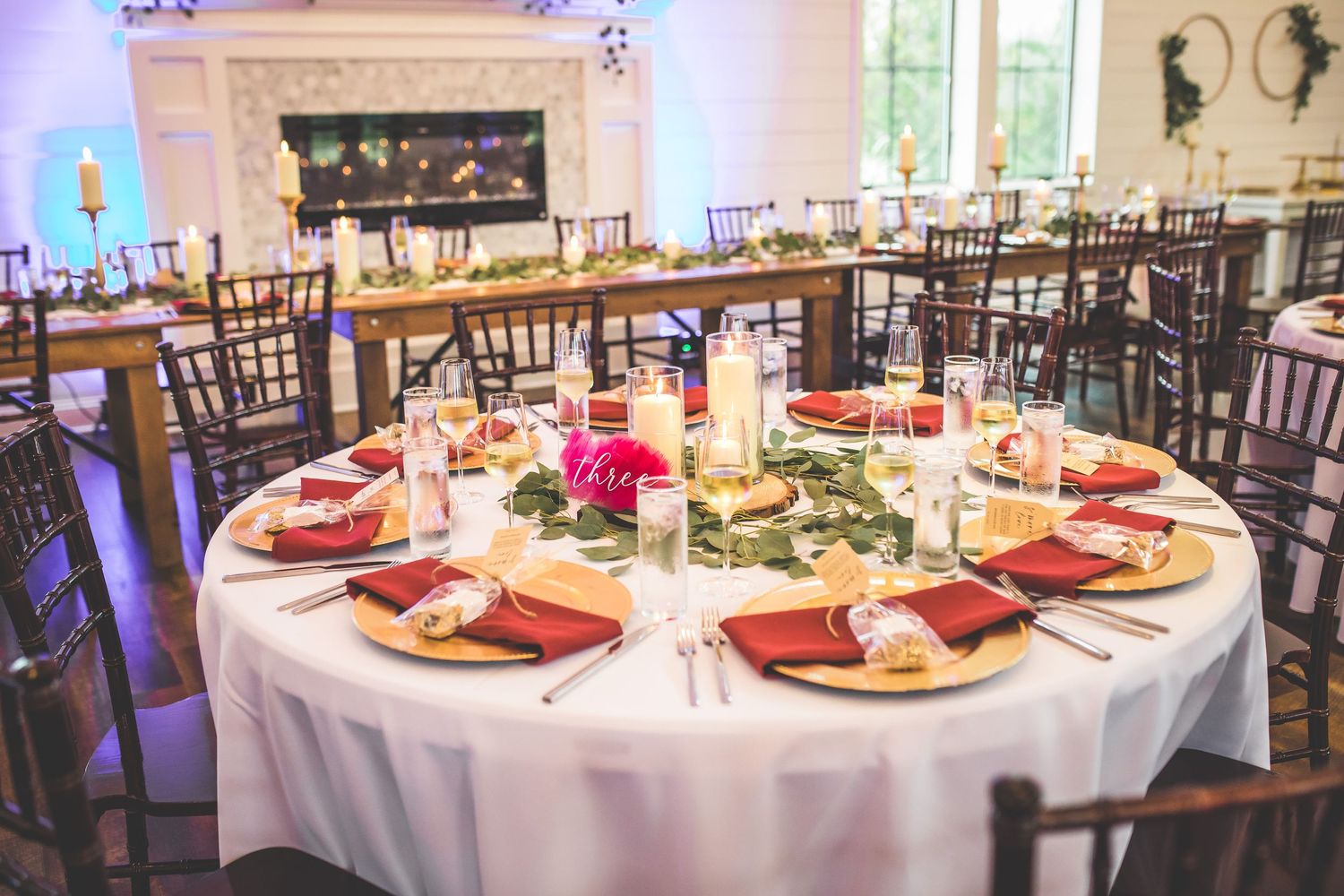 Elegant wedding reception setup with round tables and burgundy accents.