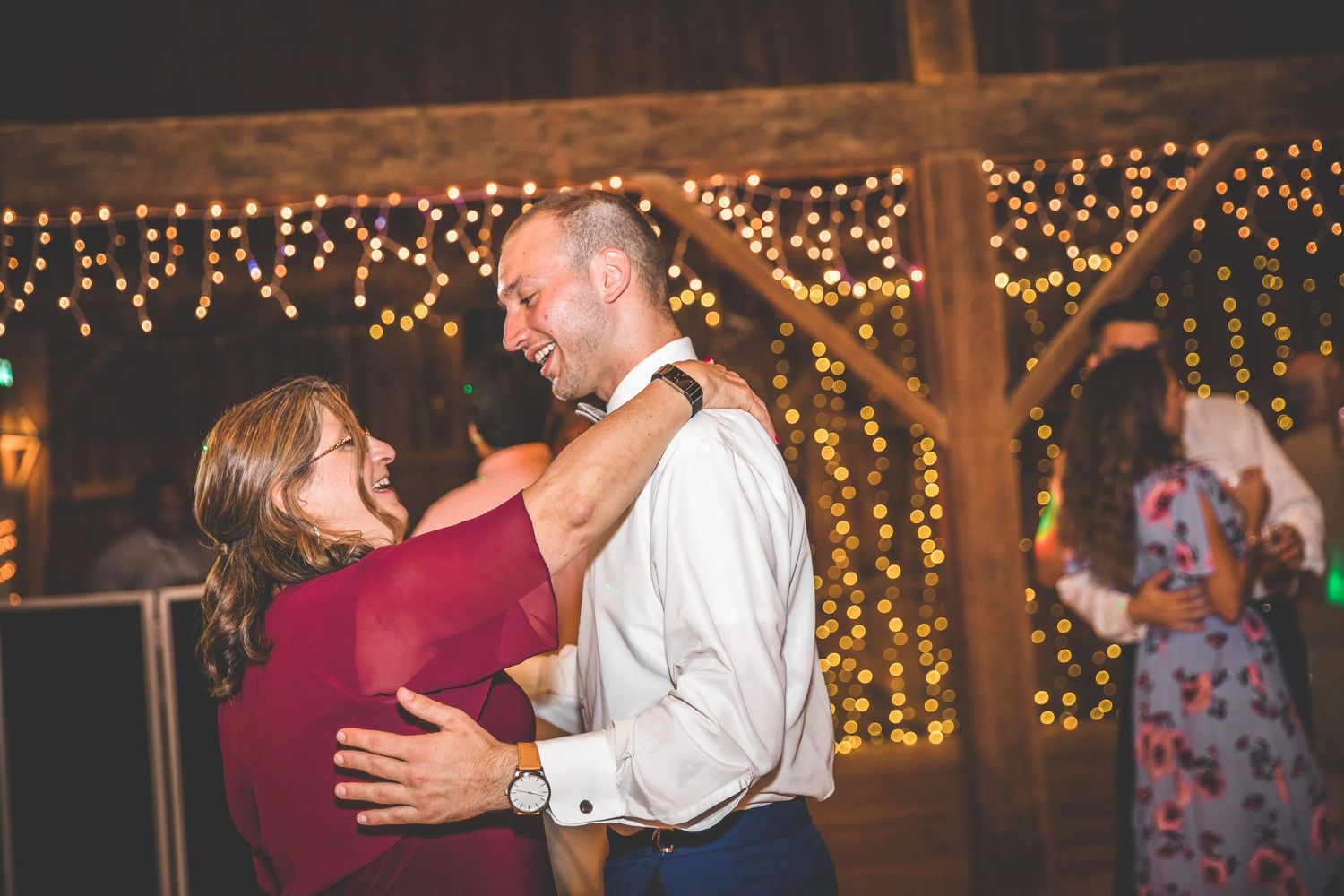 Rustic barn wedding reception with string lights and dancing guests.