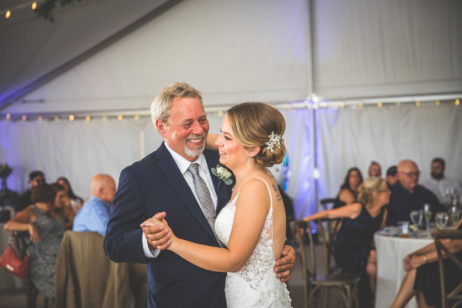 Emotional wedding dance captured in a sequence of photos under a white tent with string lights.