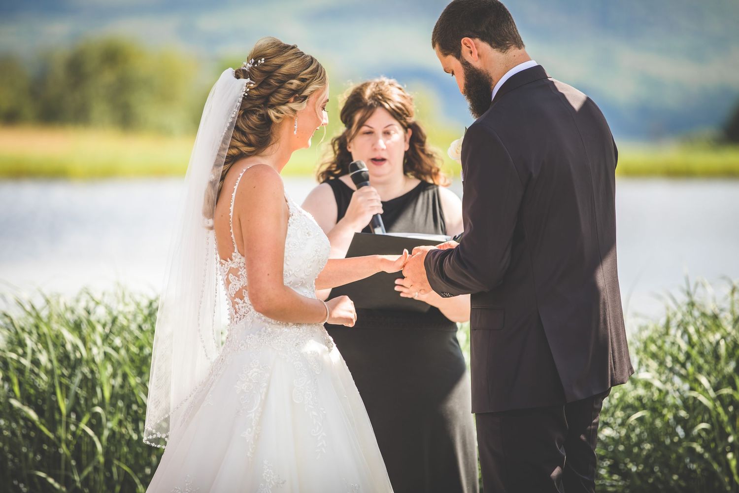 An emotional exchange of vows during a lakeside wedding ceremony with mountains in view.