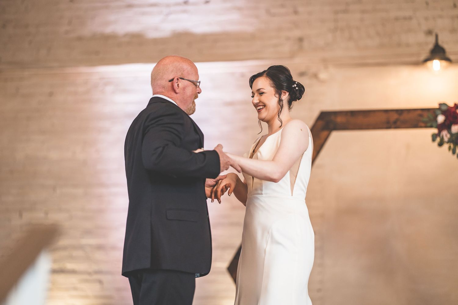 An emotional dance captured in front of a wooden hexagon arch with floral decorations.