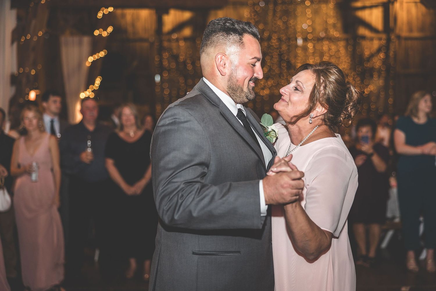 Couple shares tender moment during wedding dance in rustic barn setting.