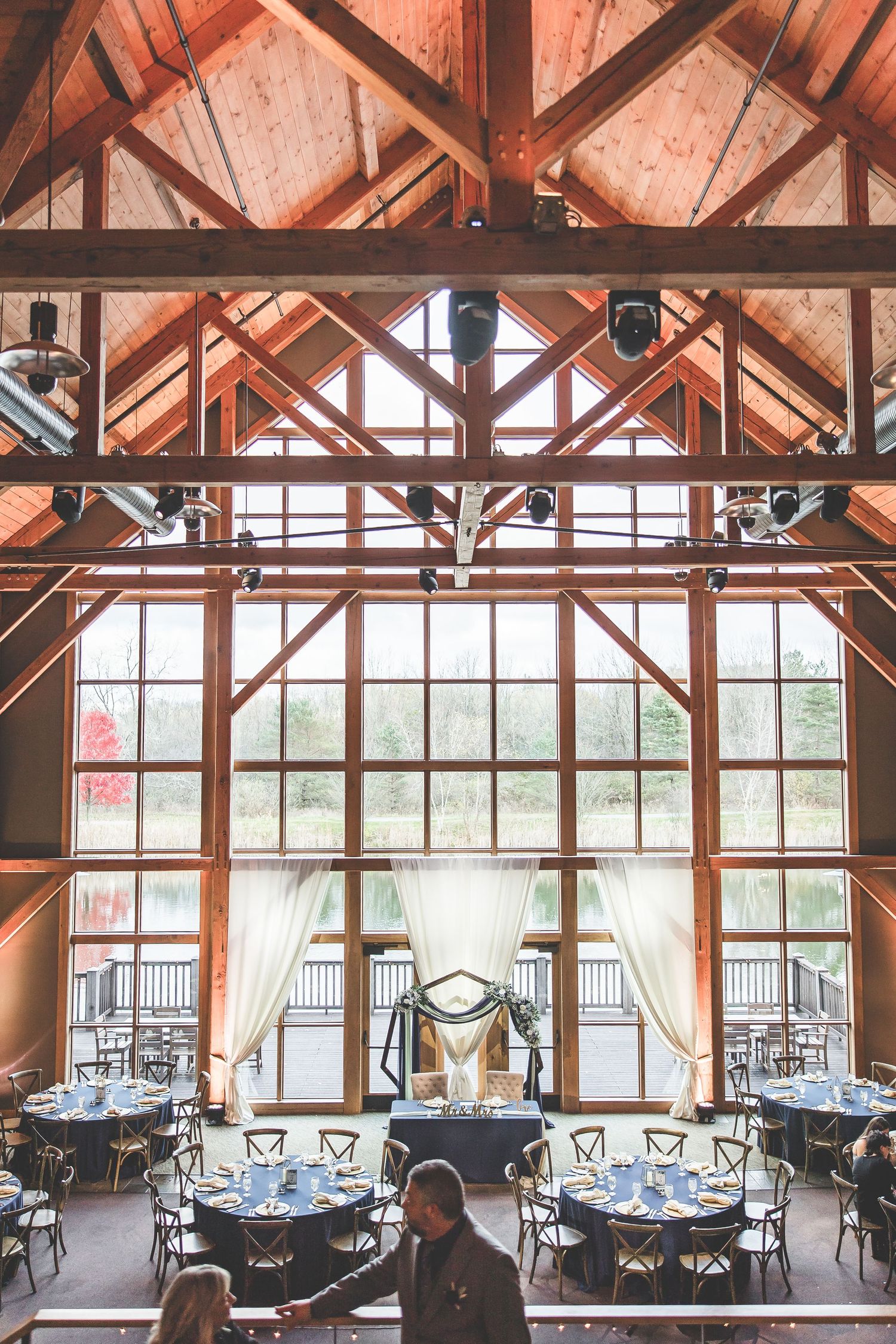 Rustic wedding venue interior with exposed wooden beams and large windows overlooking scenic views.