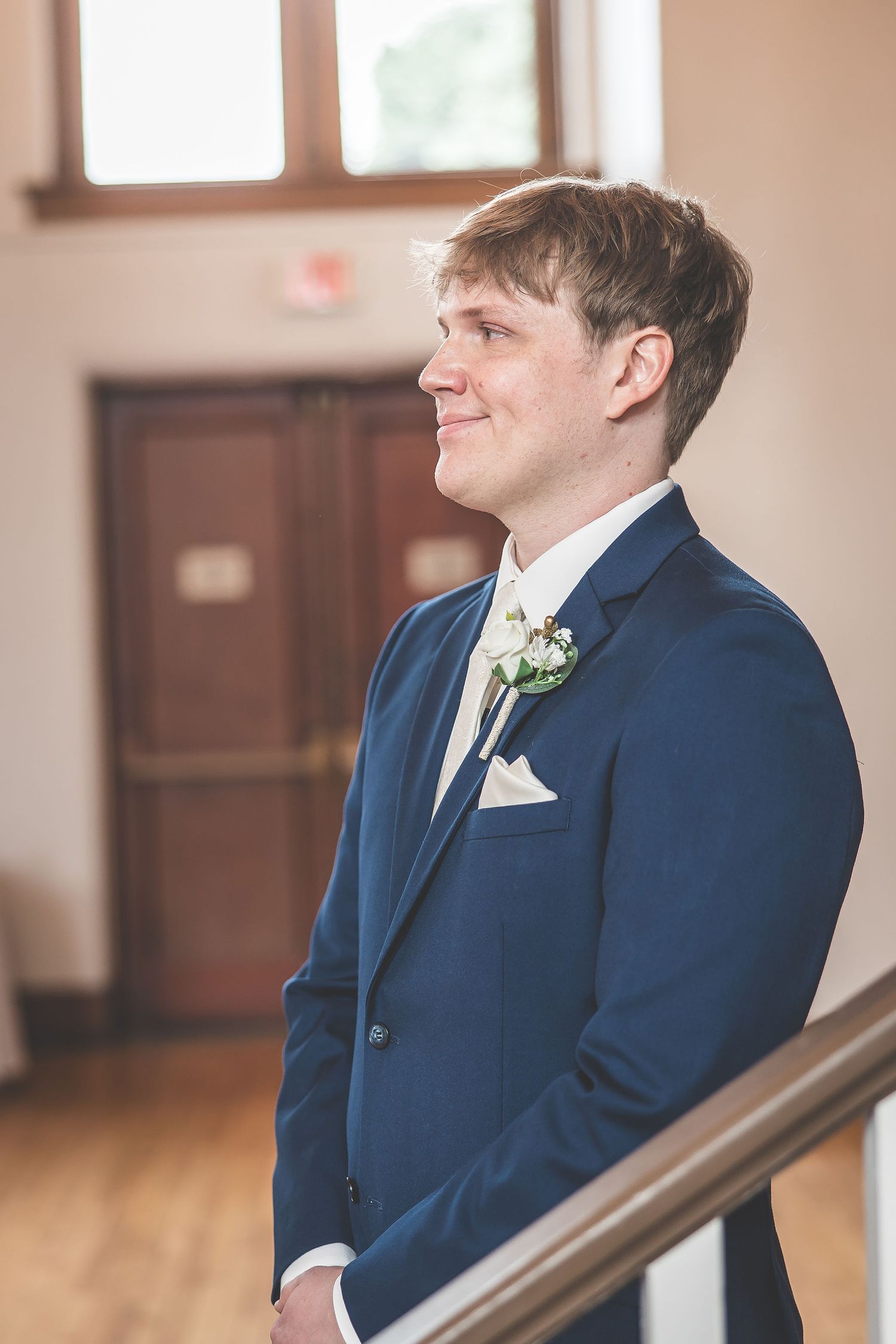 Groom in blue suit standing at altar with boutonniere.