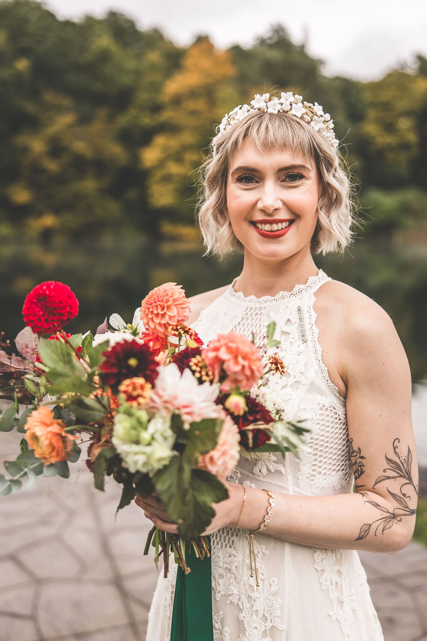 Close-up shots of a bride holding a vibrant fall bouquet with red and peach flowers.
