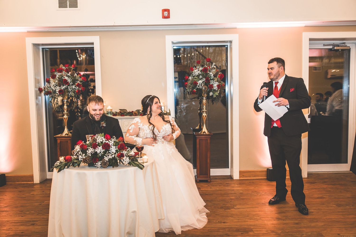 Wedding party members dance and enjoy festivities in an elegant ballroom with hardwood floors.