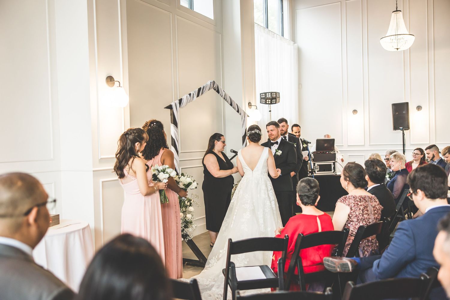Wedding guests watching ceremony in a light-filled room with modern decor elements.
