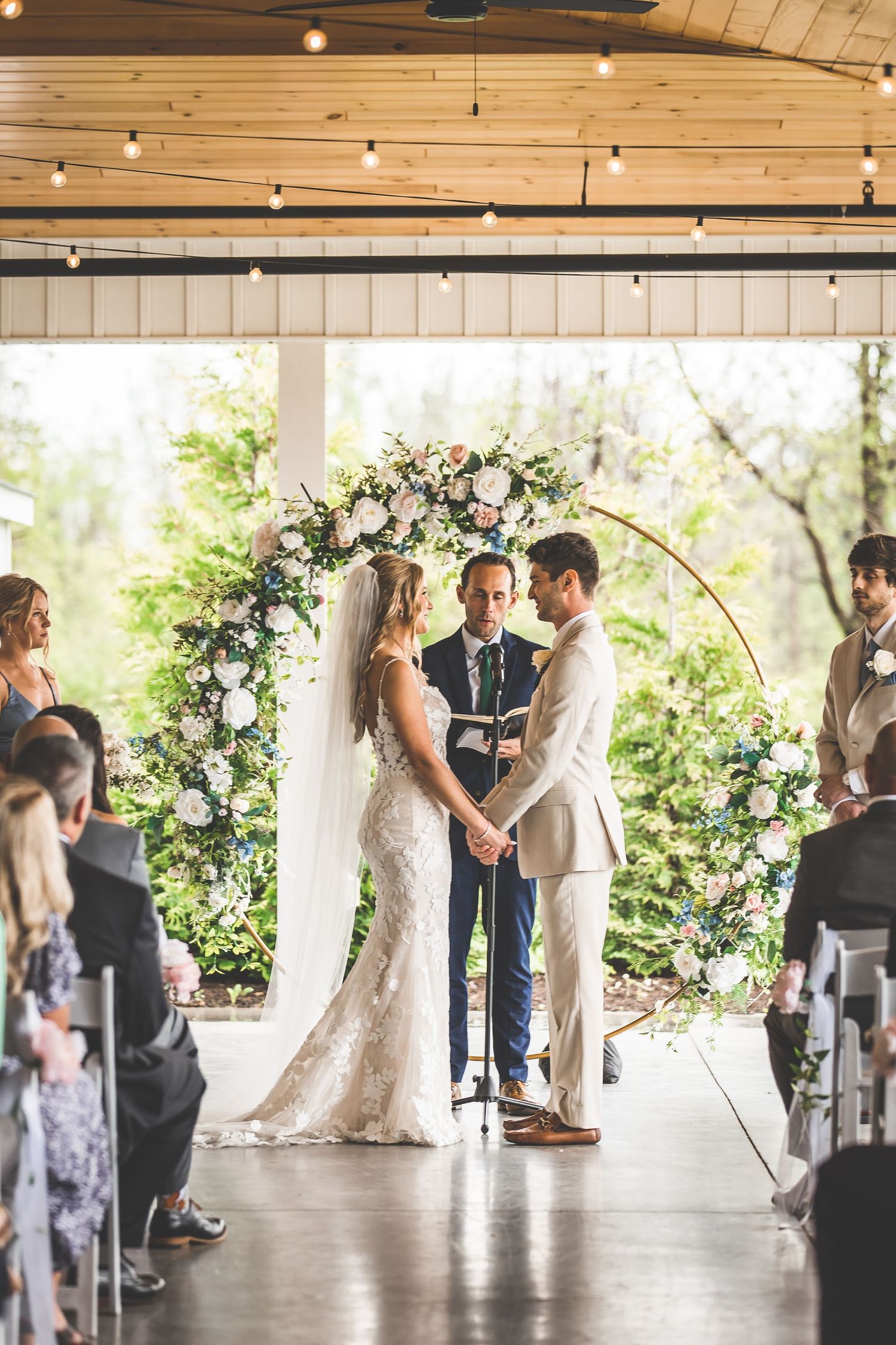 Couple exchanges vows under floral arch during intimate wedding ceremony.