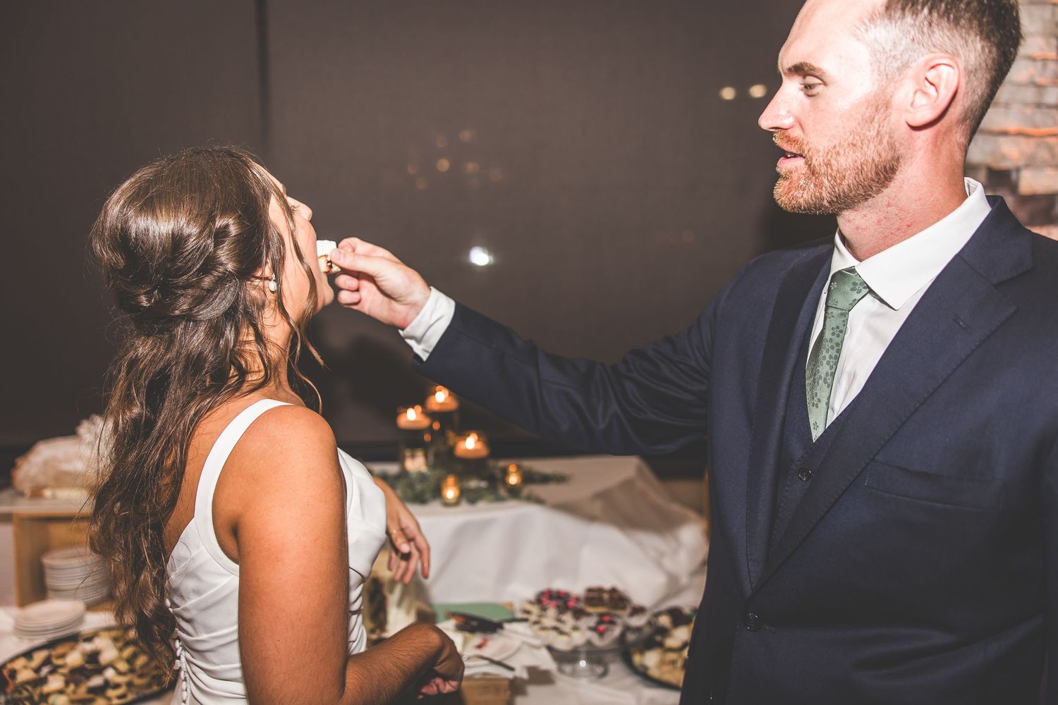 Intimate moment between couple during cake cutting ceremony at wedding reception.