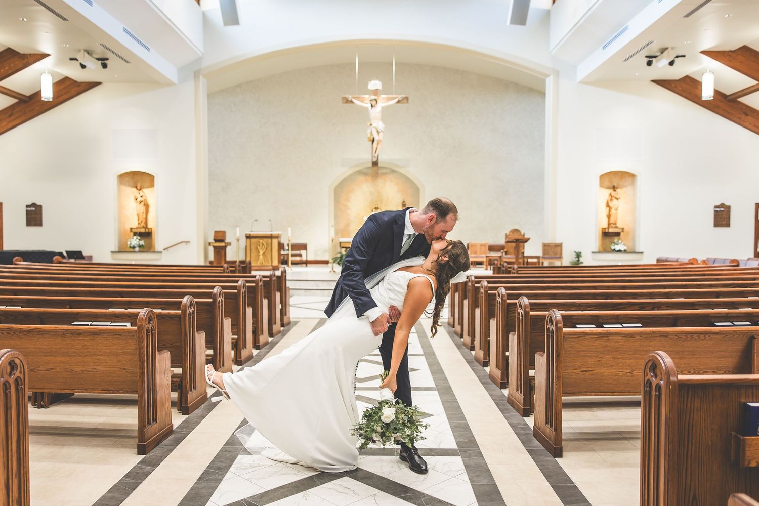 Church interior with wooden pews and vaulted ceiling featuring exposed wooden beams and white walls.