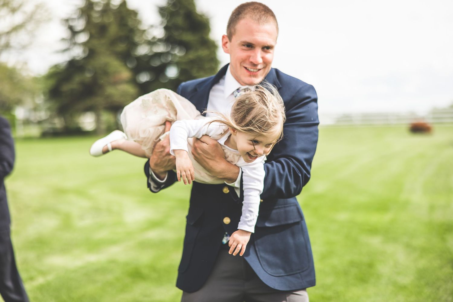 Playful candid moments captured between wedding party members outdoors.