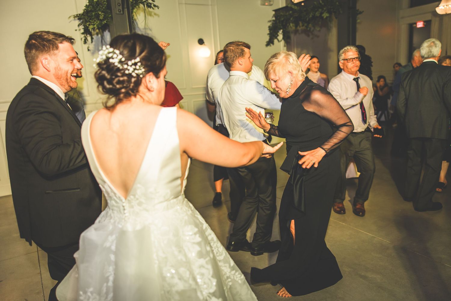 Joyful wedding reception with guests dancing in an elegantly decorated indoor space.