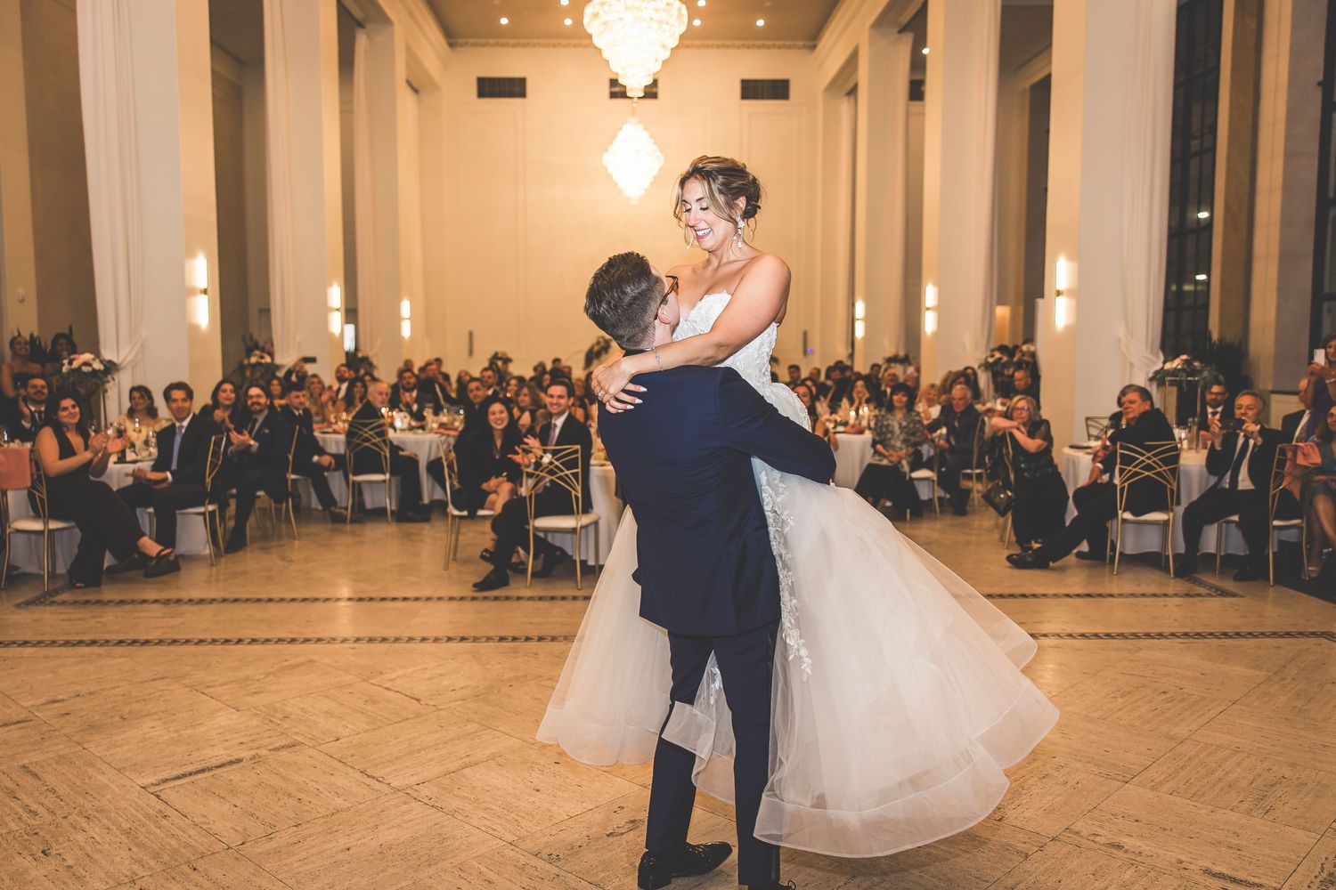 Elegant dance performance unfolds beneath crystal chandeliers in classic ballroom setting.