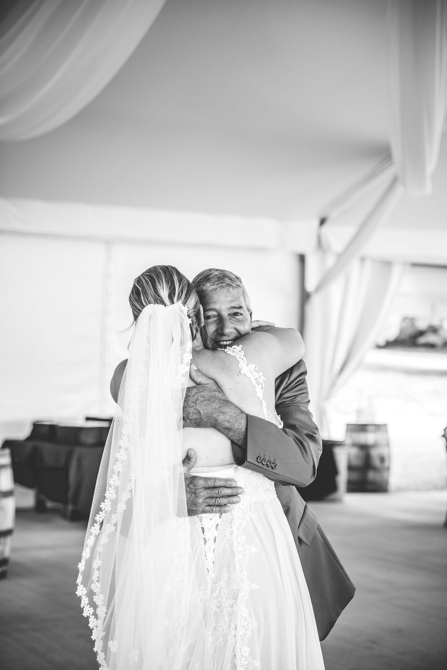 A black and white candid moment of an emotional embrace during a wedding dance.