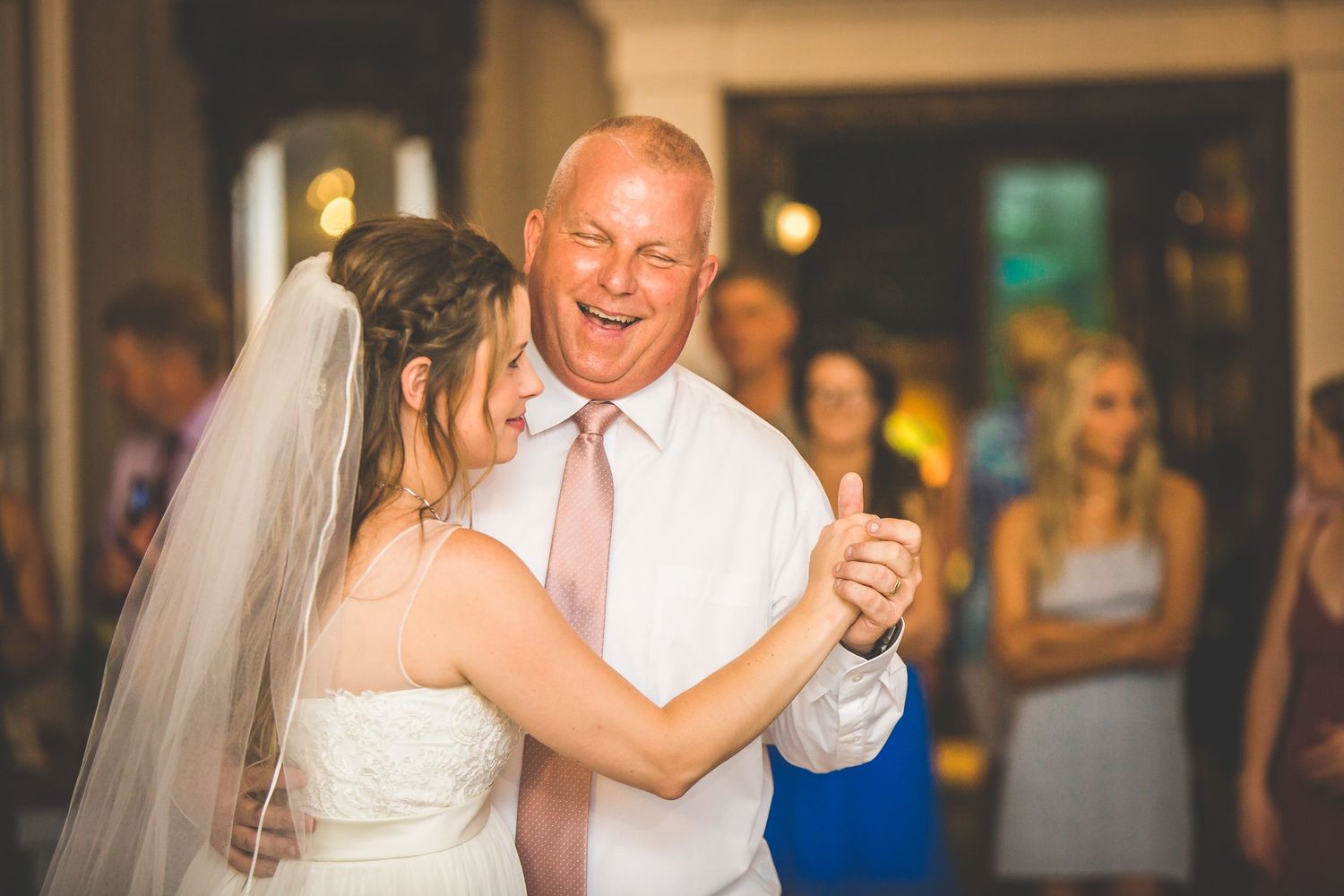 Guests dance together during a wedding reception in an elegantly lit indoor venue.