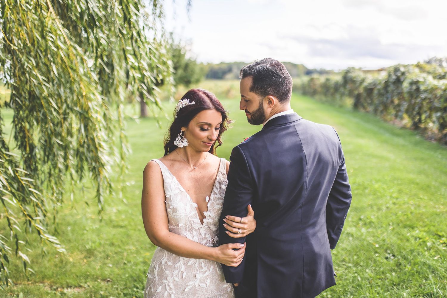 Couple shares intimate dance moment in sunlit vineyard setting.
