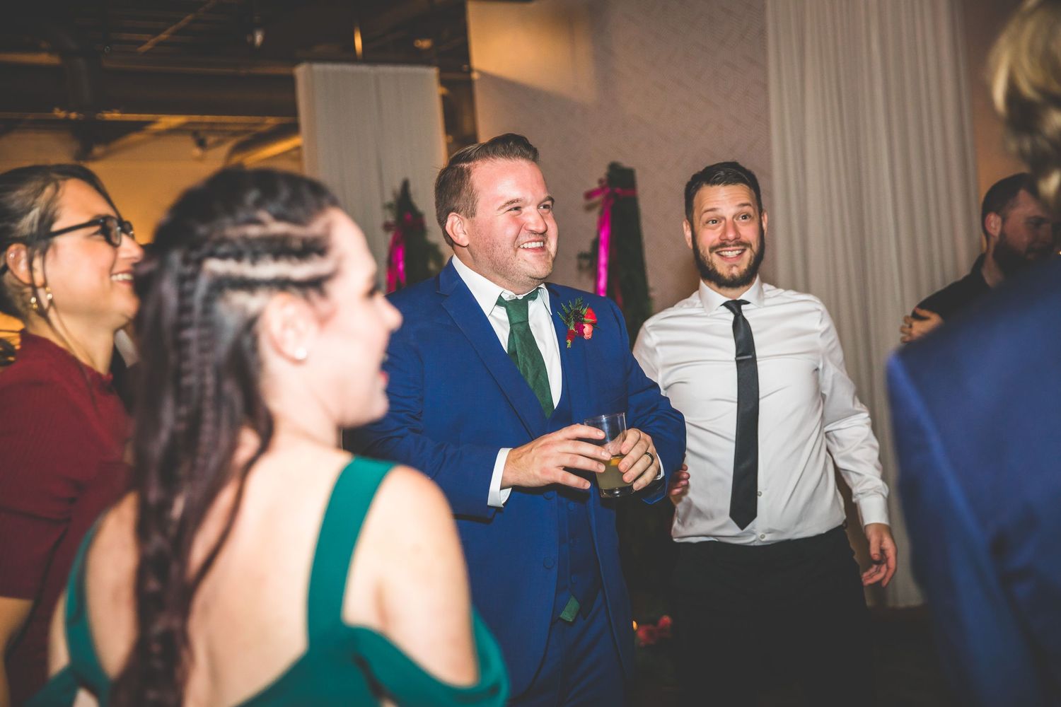 Wedding guests enjoying themselves on the dance floor under ambient lighting.
