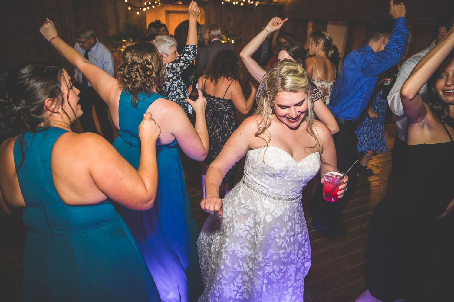 Wedding guests dancing and having fun under string lights at an evening celebration.