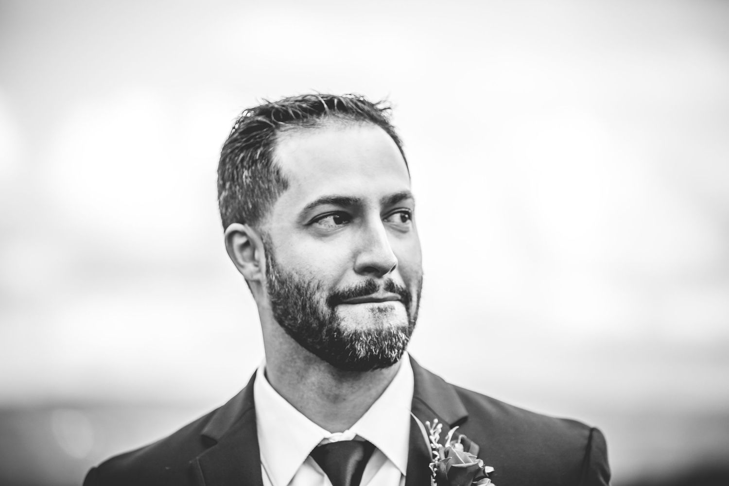 Black and white portrait showing joyful expression and boutonniere detail.