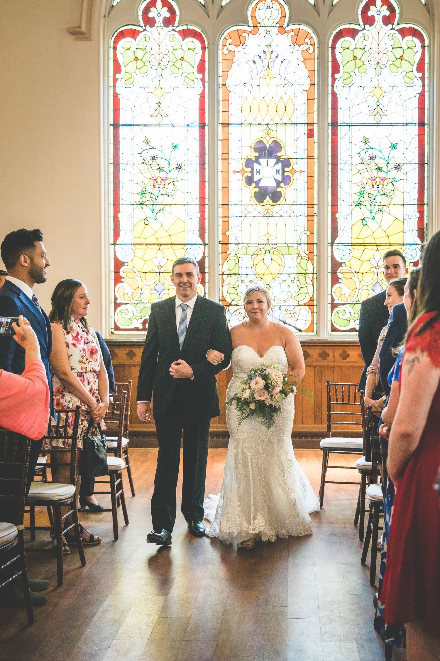 Wedding ceremony in a church with beautiful stained glass windows and wooden pews.