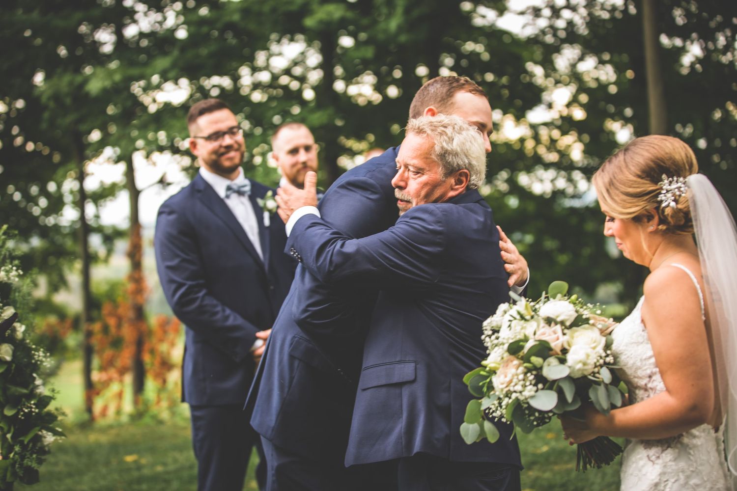 Wedding party shares joyful moments during an outdoor celebration with natural bokeh background.