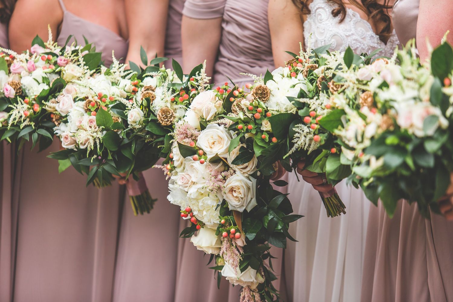 Row of elegant bridesmaids bouquets featuring blush and cream roses with eucalyptus leaves.