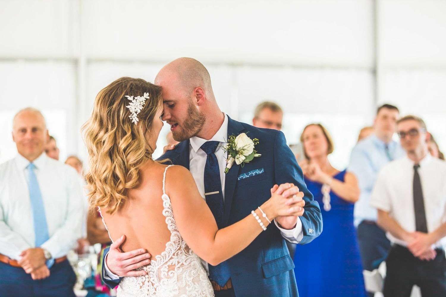 Wedding guests dance and celebrate on a white dance floor during a reception.