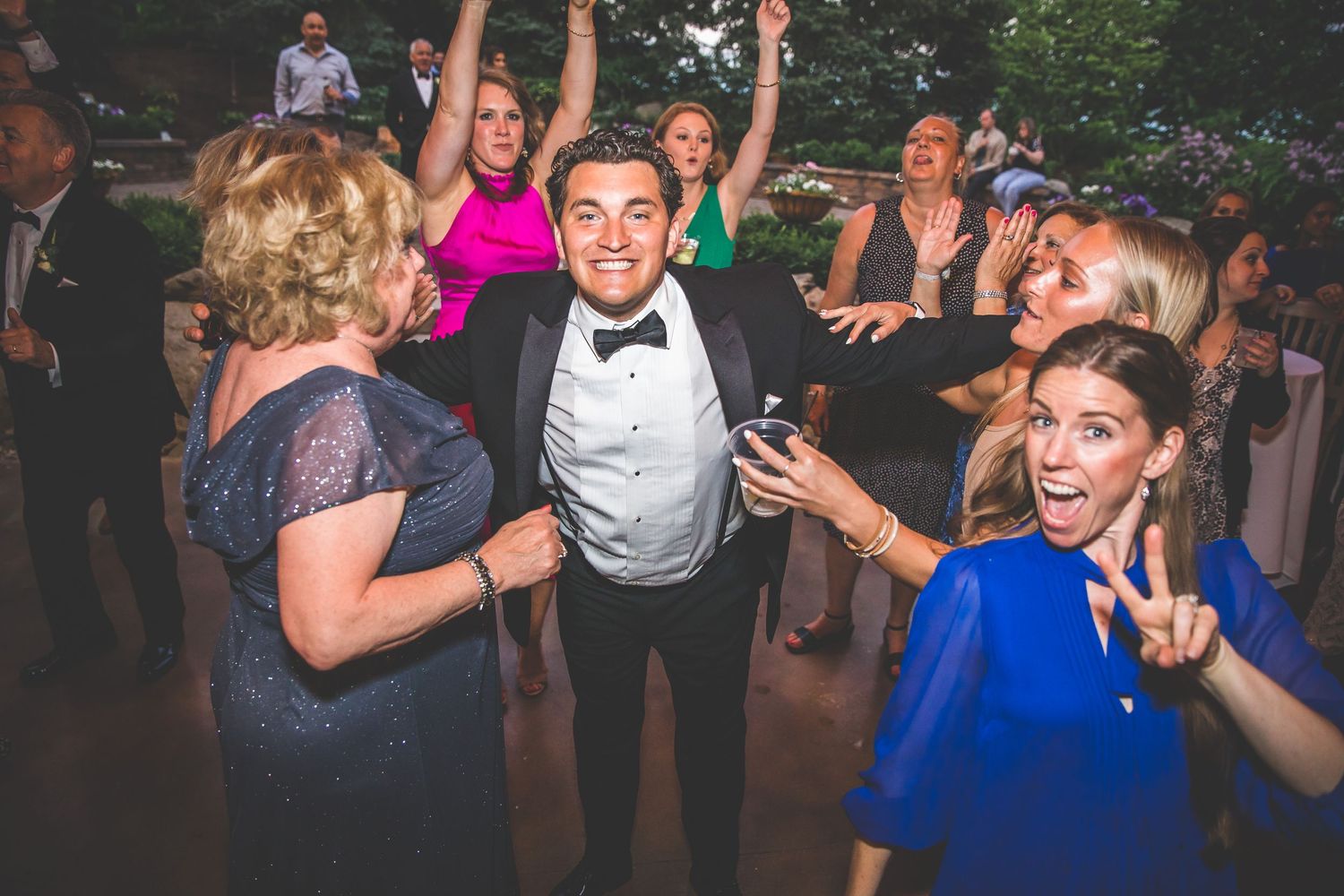 Wedding party and guests dancing energetically on the dance floor during reception celebrations.