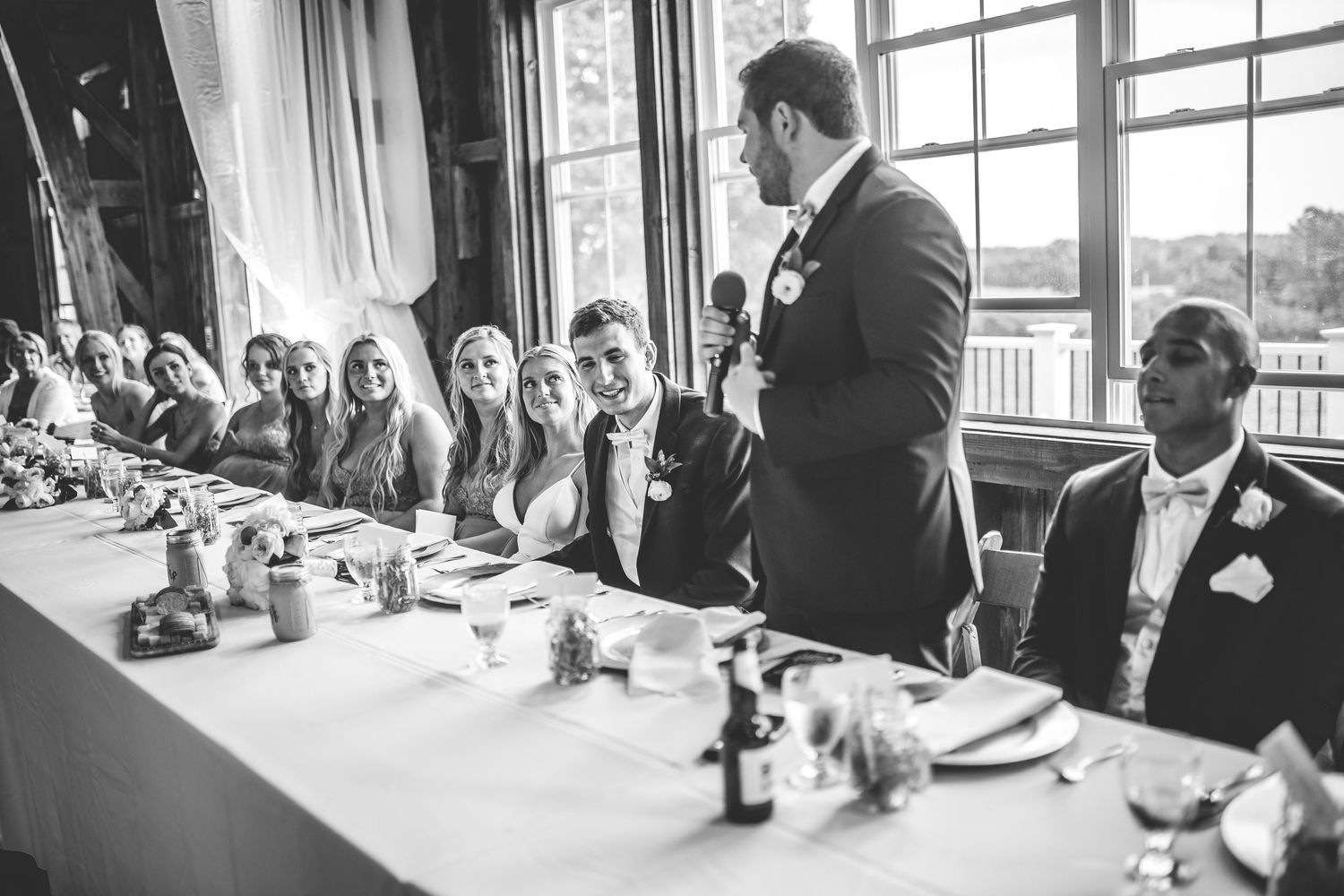 Wedding reception speech being delivered at head table with guests listening intently.