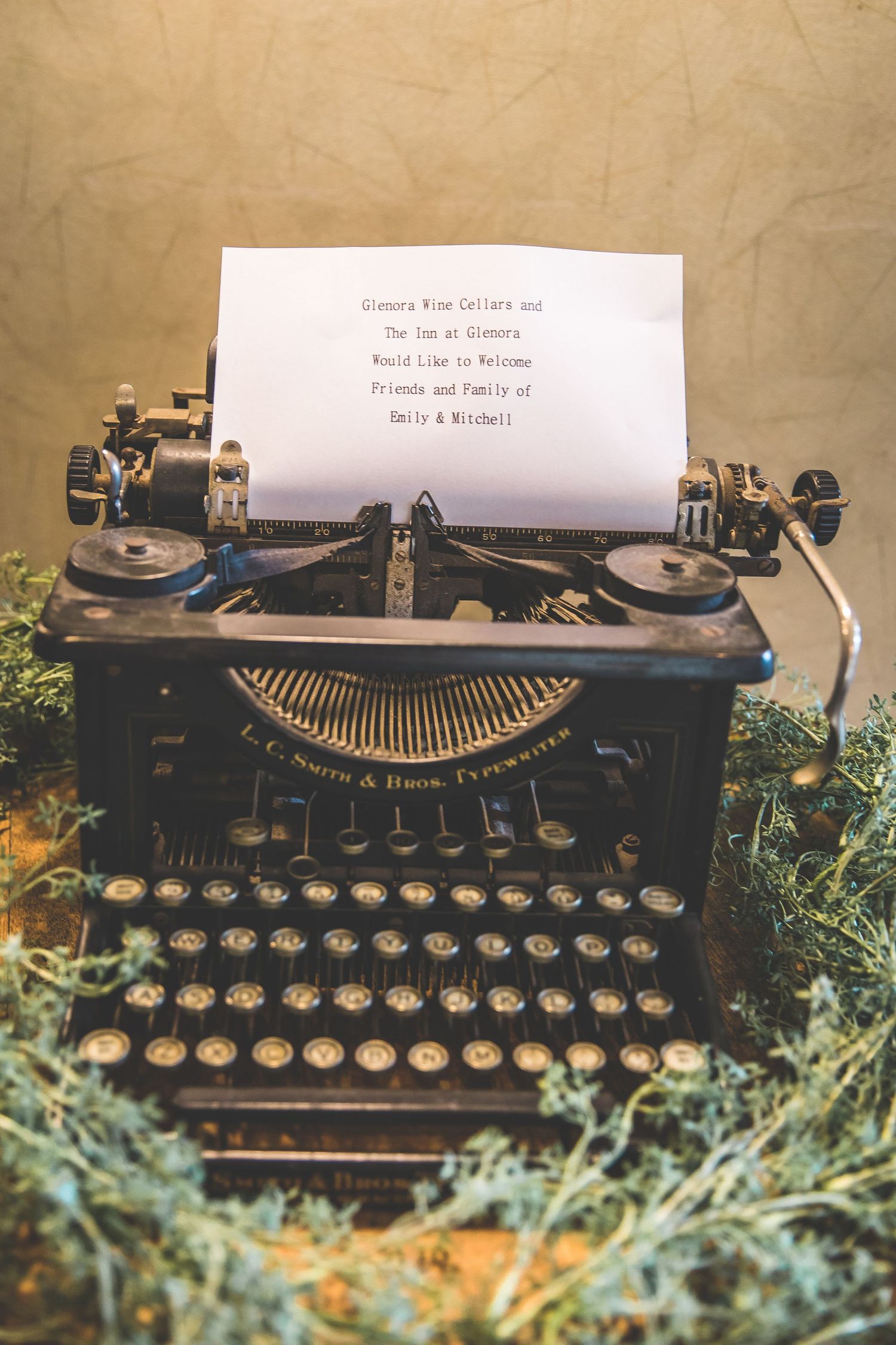 Vintage typewriter with paper surrounded by greenery as wedding decor.