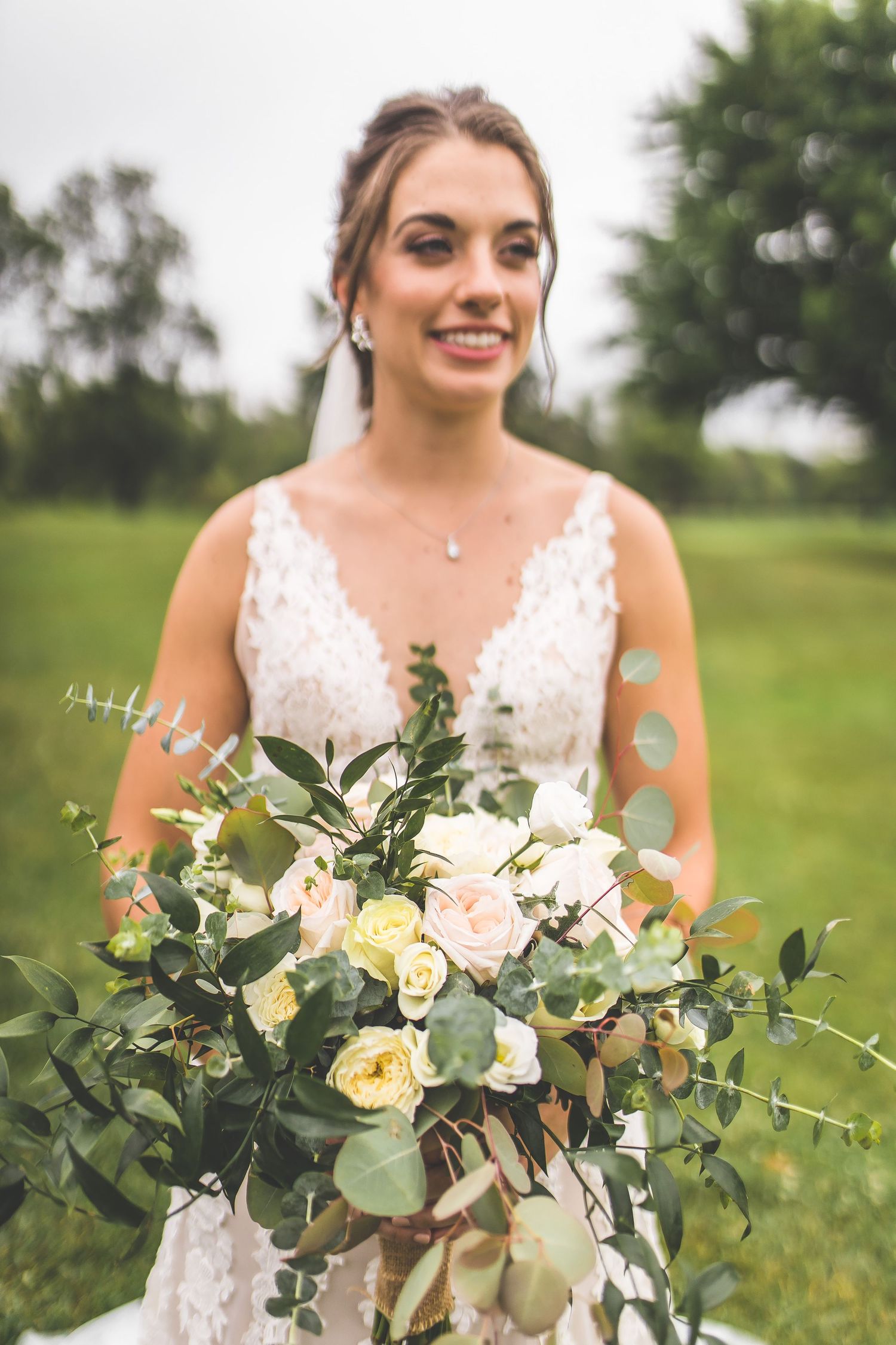 Close-up shots of a beautiful bridal bouquet with white roses and eucalyptus against a green background.