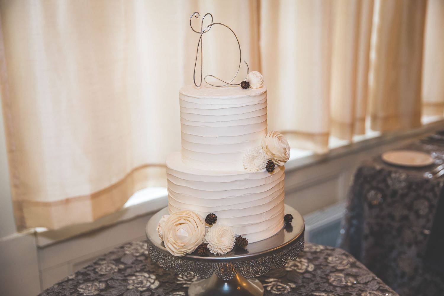 White tiered wedding cake with simple elegant design displayed on dark table.
