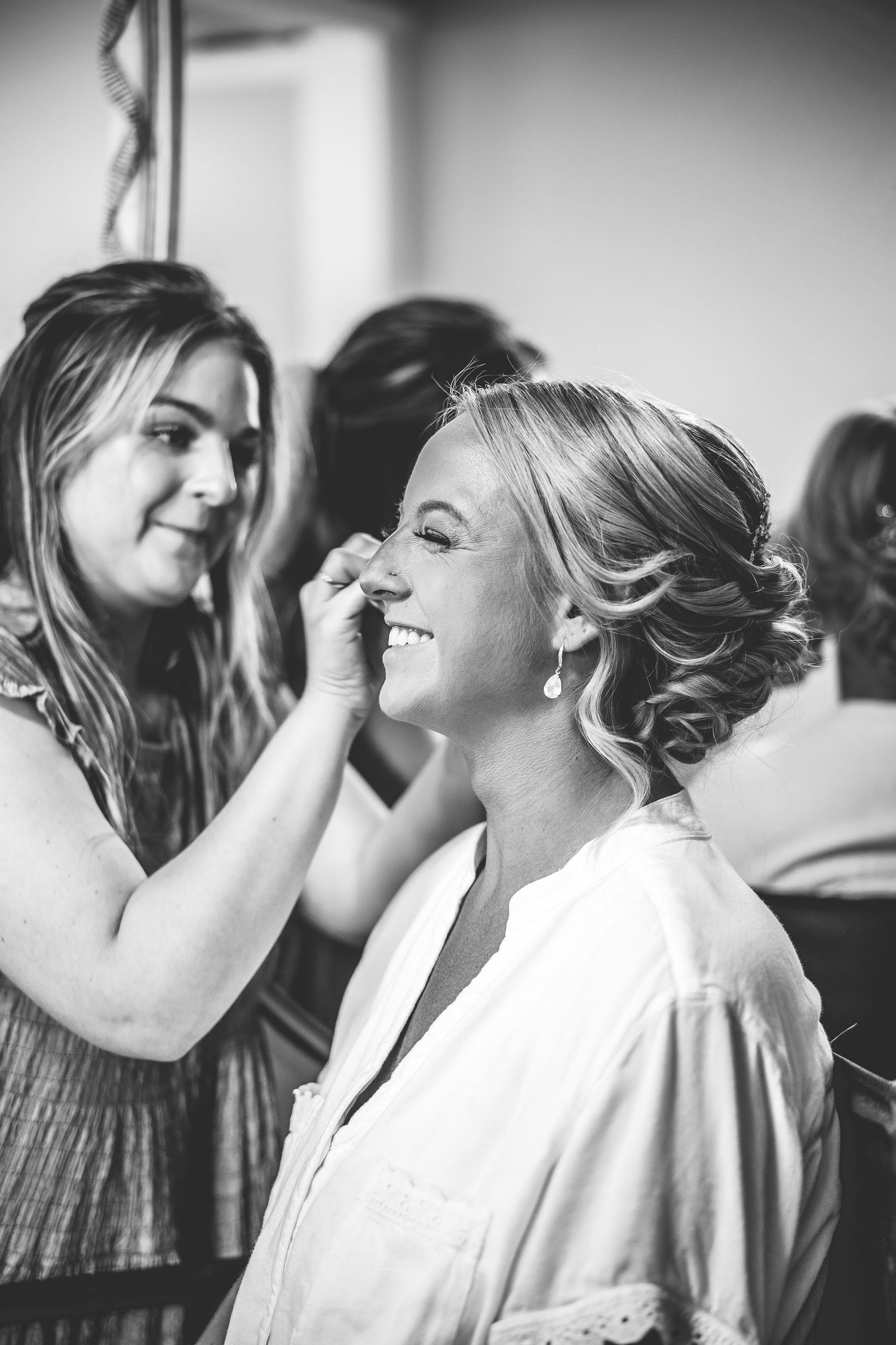 Black and white photo of wedding preparation with makeup being applied.