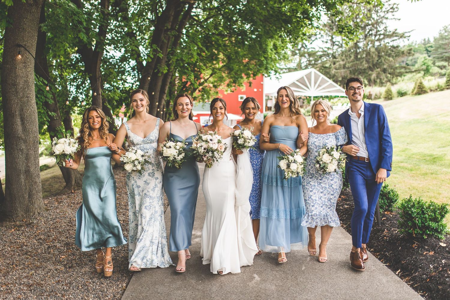 Wedding party walking together outdoors in coordinated blue and floral attire.