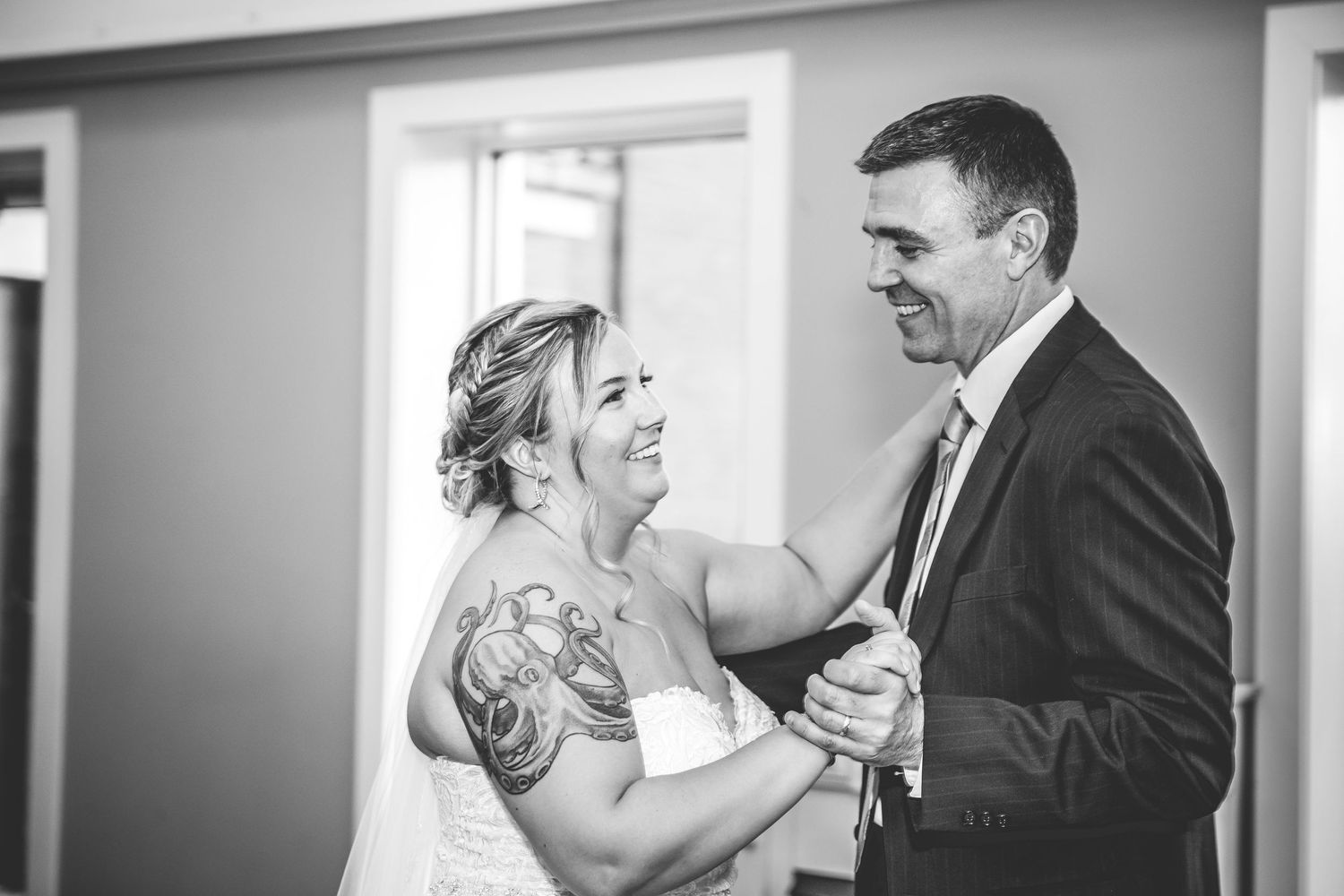 Black and white photo of couple sharing laughter during wedding reception.