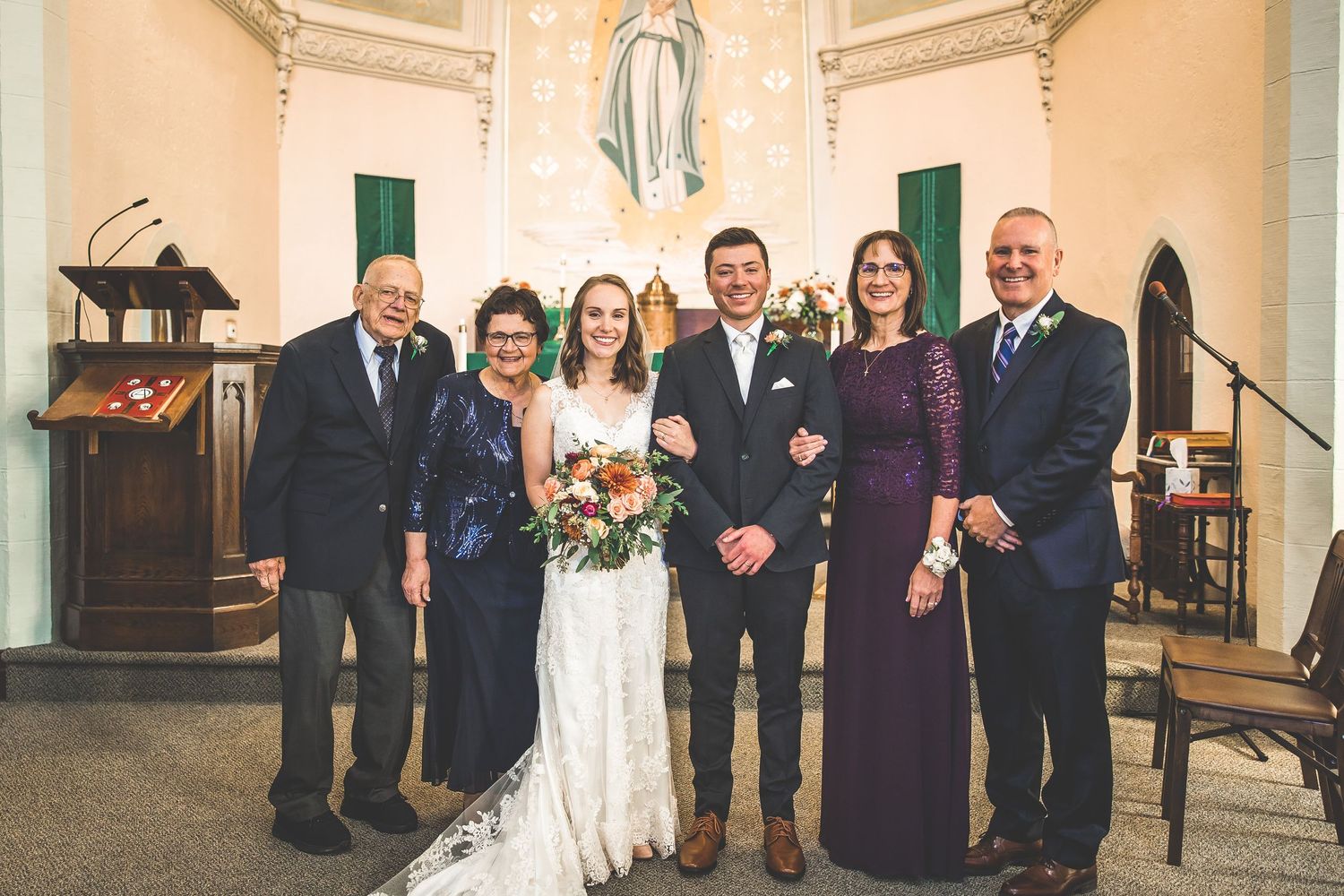 Wedding party members gathered in a church with ornate architectural details.