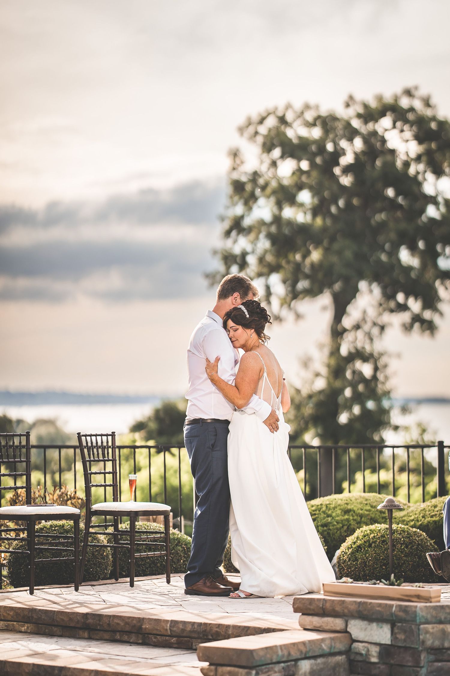 Sunset wedding portraits on a stone patio with wrought iron railings and garden views.