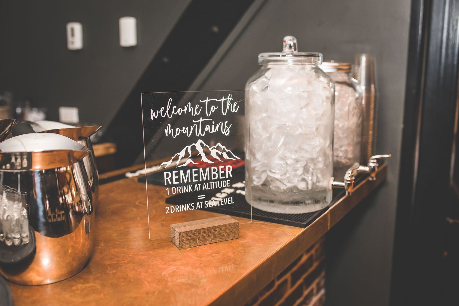 Rustic wedding decor featuring a welcome sign and drink dispensers on wooden table.