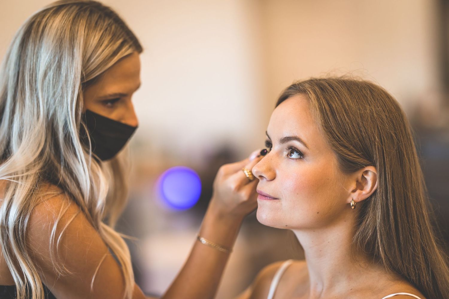 Professional makeup artist applying cosmetics during bridal preparation.
