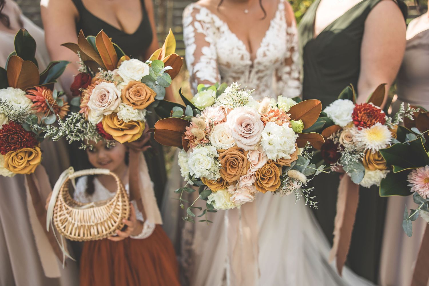 Wedding party holds coordinated floral bouquets in shades of peach and white.