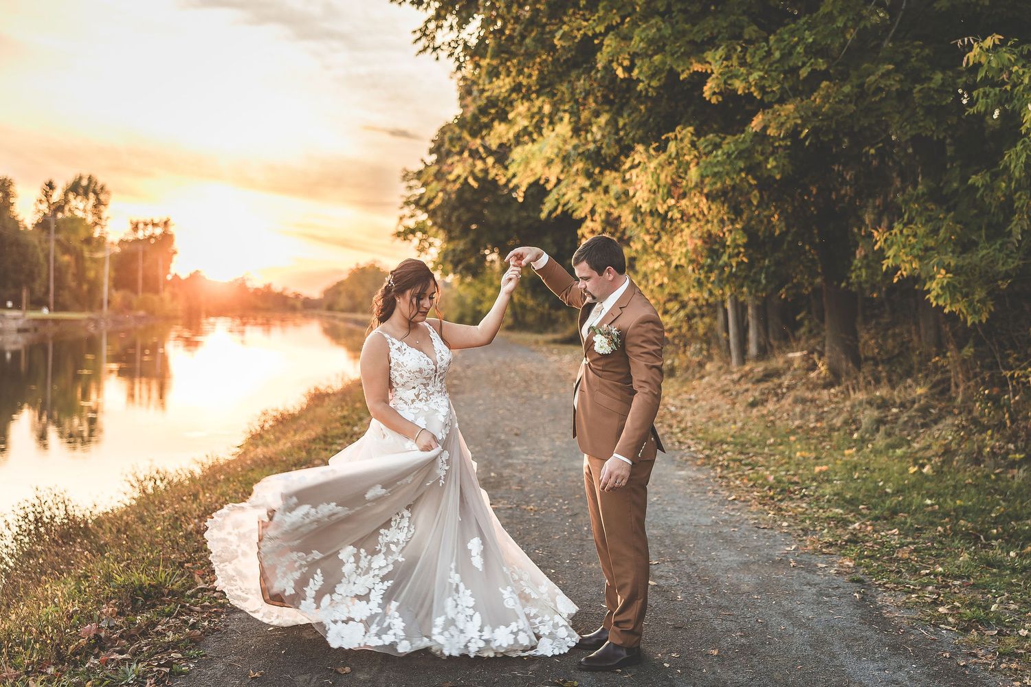 Wedding couple shares romantic moment on path during golden hour sunset.