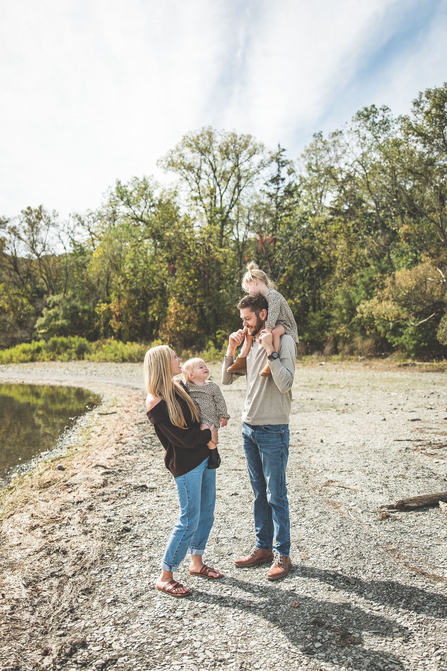 People walking together on a rocky shoreline during a sunny autumn day.