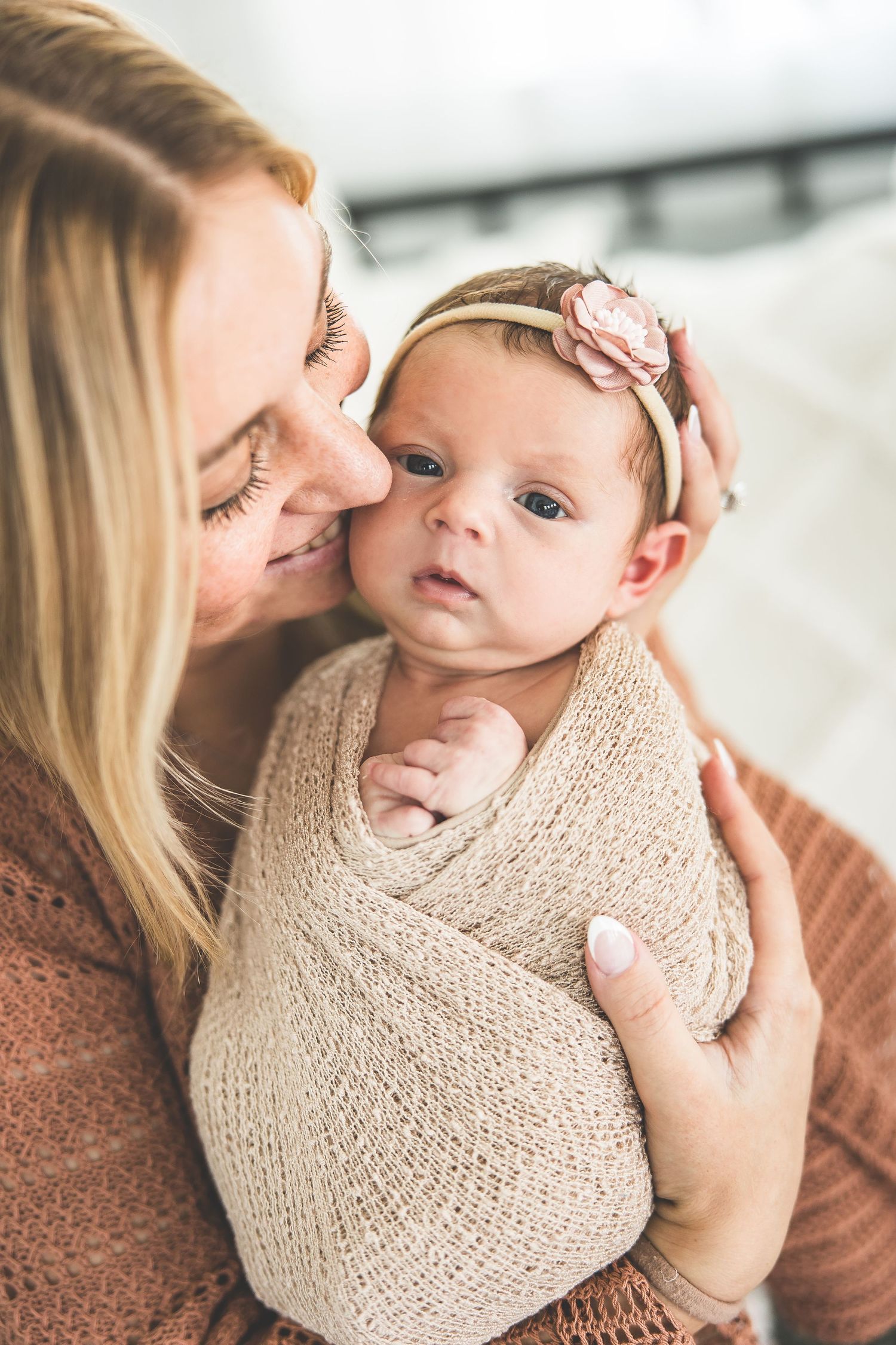 A tender moment between parent and baby wrapped in a knit blanket.