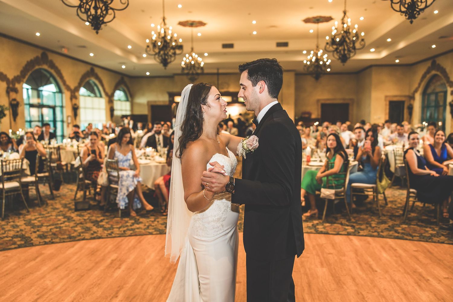 Elegant ballroom wedding reception with chandeliers and dancing couples.