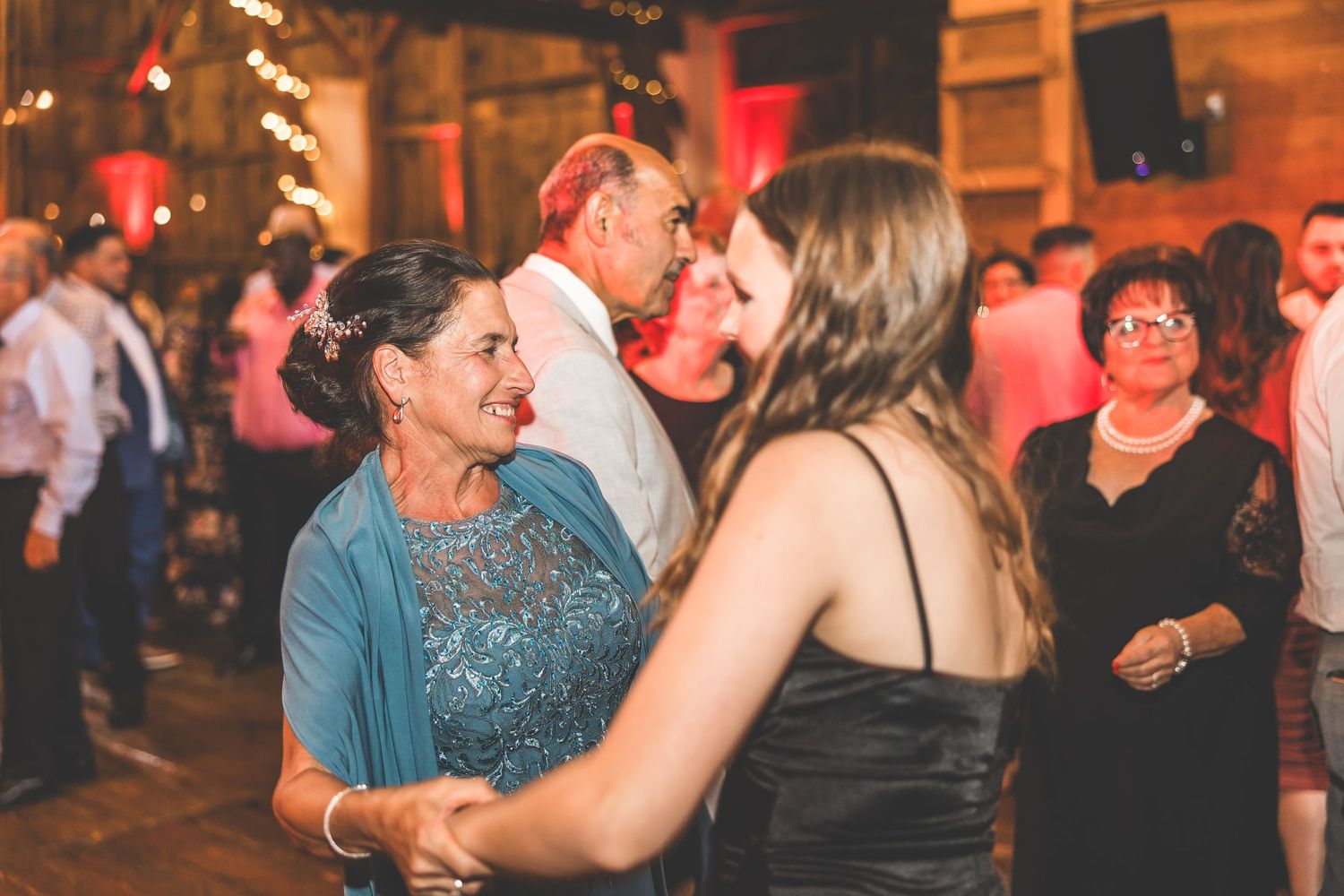 Wedding guests dancing and enjoying themselves on the dance floor in a rustic barn setting.