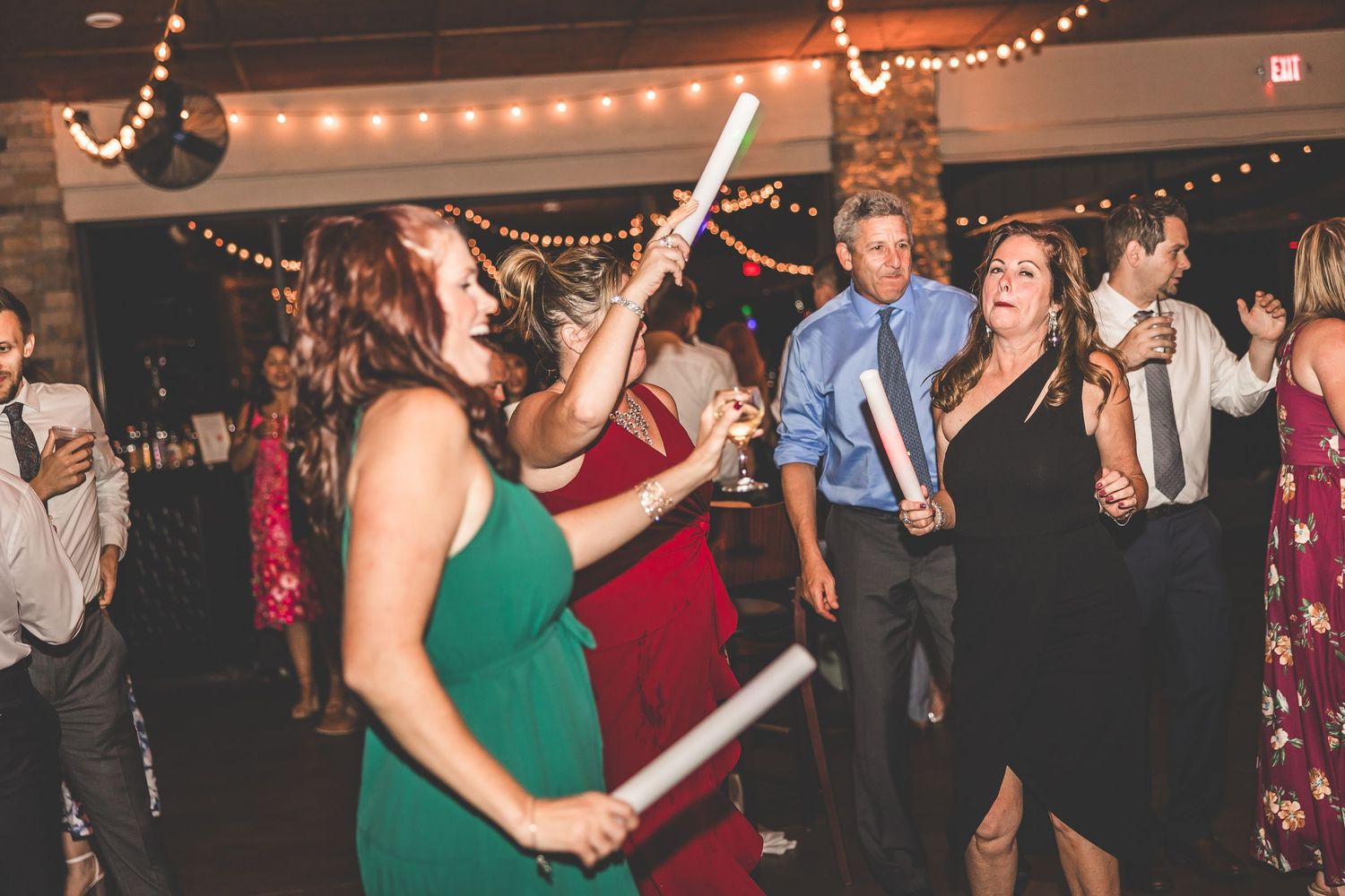 Guests dancing and celebrating on a crowded dance floor at an evening wedding reception.