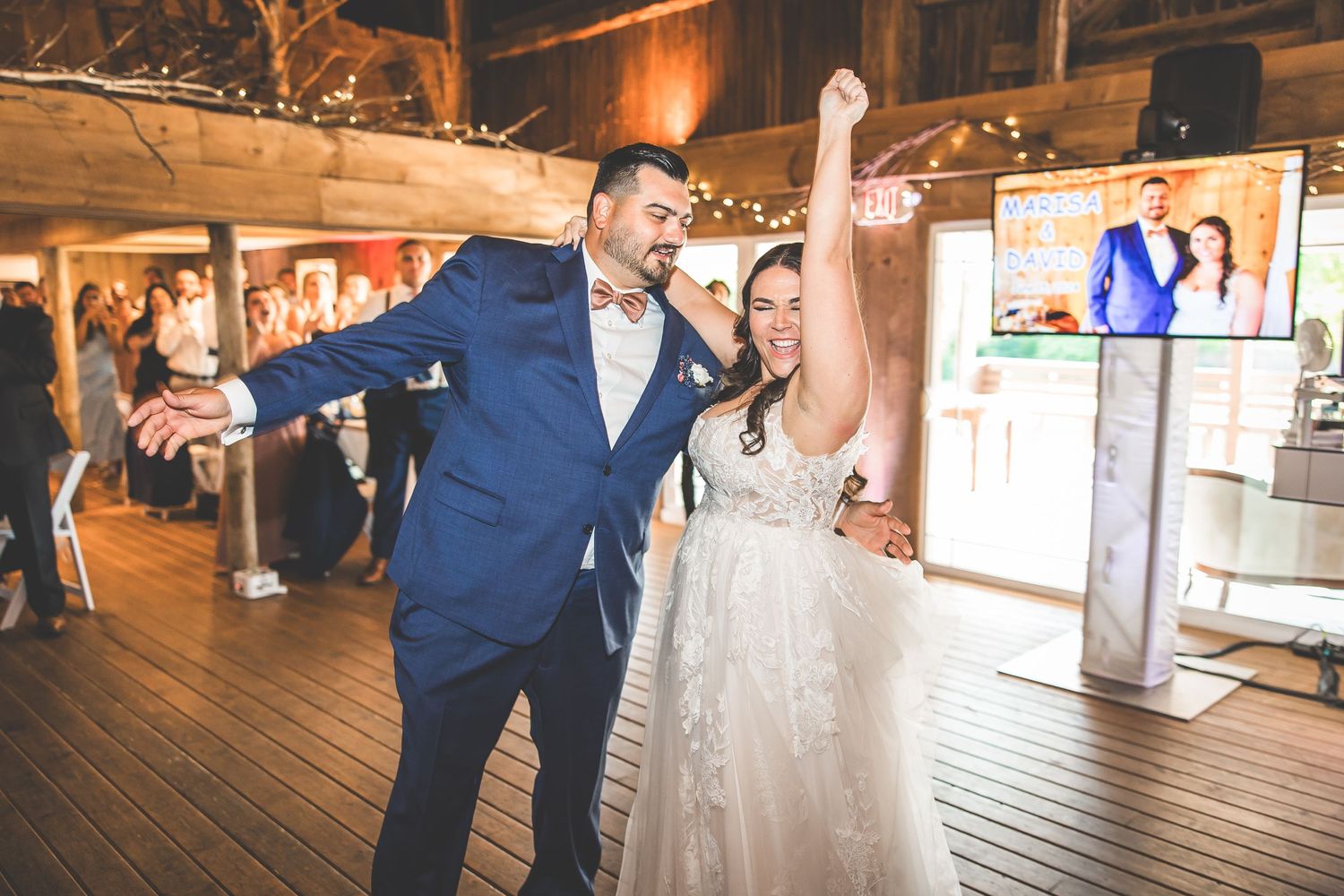 Wedding reception dance floor moments in a warmly lit rustic barn venue.